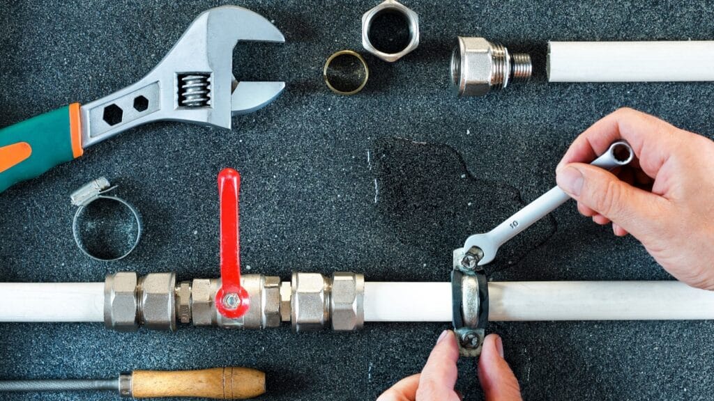 Plumber repairing a pipe valve with an adjustable wrench in Punta Gorda