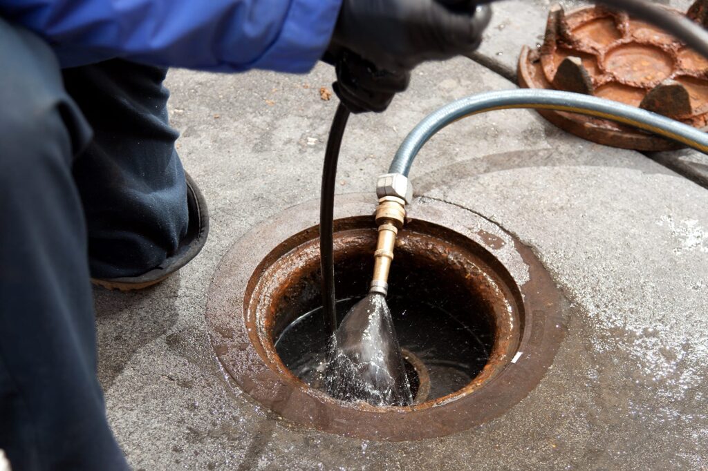 Plumber hydro jetting a sewer line through a manhole in Punta Gorda