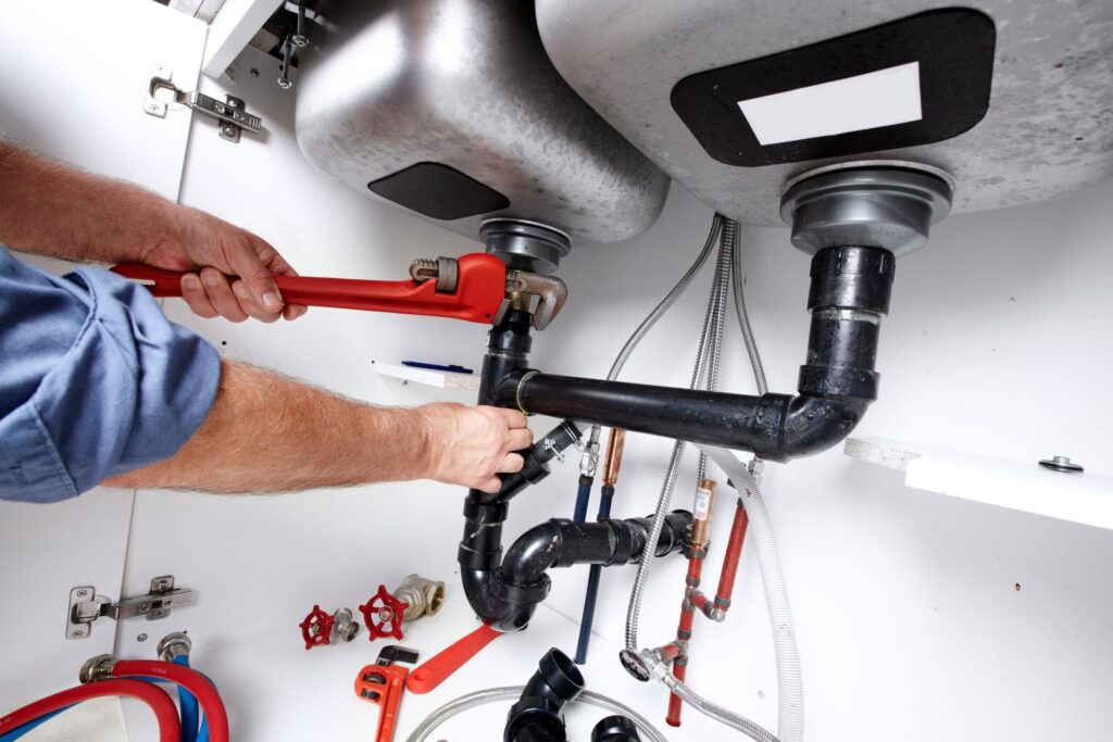 Plumber repairing drain pipes beneath a kitchen sink in Punta Gorda