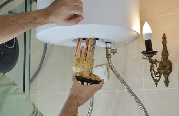 Technician removing mineral buildup from a water heater in Punta Gorda